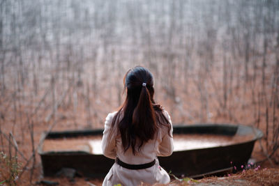 Rear view of woman sitting in forest