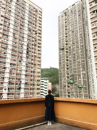 Rear view of man standing against buildings in city