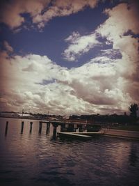 Pier on sea against cloudy sky