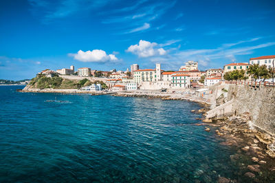 Buildings by sea against sky