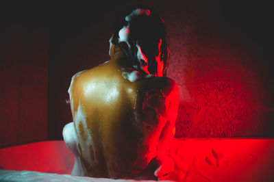 Rear view of naked young woman taking bath