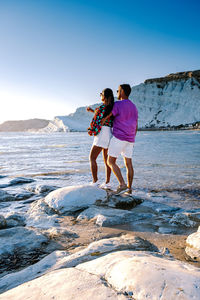 Woman standing on rock at beach against sky