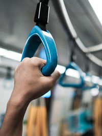 Close-up view of a hand holding the grab handle in a train