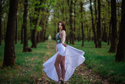 Woman with umbrella on field in forest