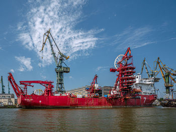 Cranes at commercial dock against sky