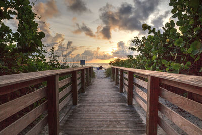 Lone man on a boardwalk leading toward delnor-wiggins state park at sunset in naples, florida.