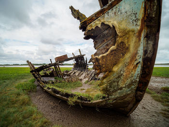 Abandoned boat on beach against sky