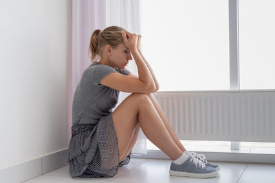 Mental health. depressed young woman in gray shirt and skirt sitting on the floor