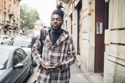 Portrait of young man standing on street in city