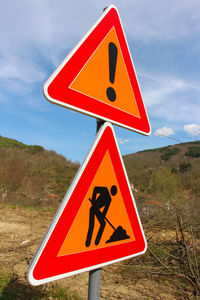 Close-up of road sign against sky