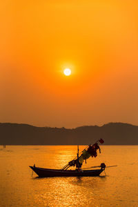 Silhouette boat in sea against orange sky