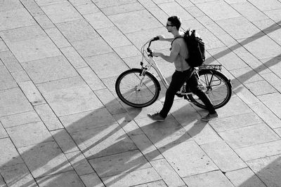 High angle view of man walking with bicycle on footpath