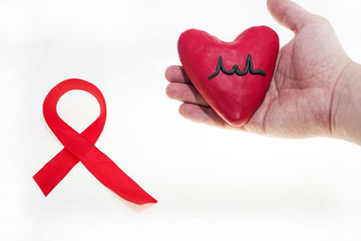 Close-up of hand holding heart shape over white background