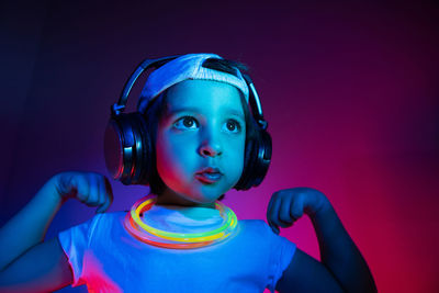 Cyberpunk boy child in a white t shirt and large headphones listening to music on the background 