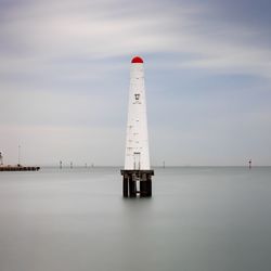 Lighthouse by sea against sky