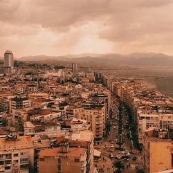 High angle view of road amidst buildings in city against cloudy sky