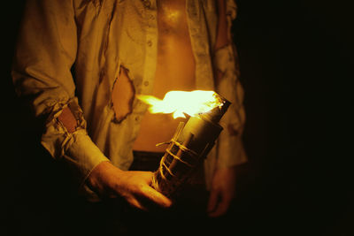 Midsection of man holding burning candle