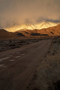 Dirt road on landscape against sky