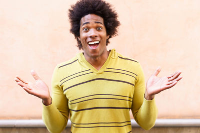 Portrait of smiling young man standing against yellow wall