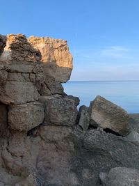 Rock formations by sea against blue sky