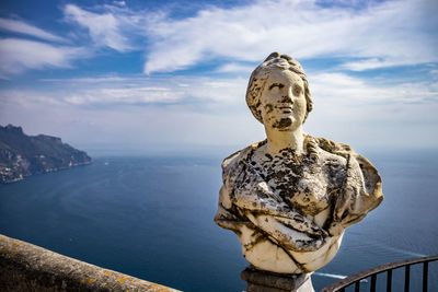 Statue by sea against sky