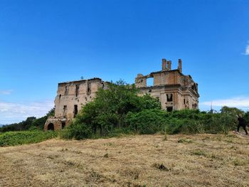 Old building on field against clear blue sky