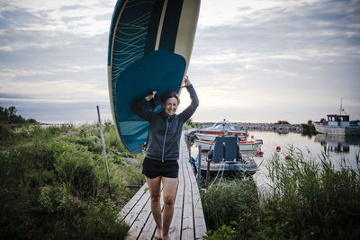 Woman carrying paddleboard at lake