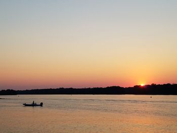 Silhouette of boat in sea during sunset