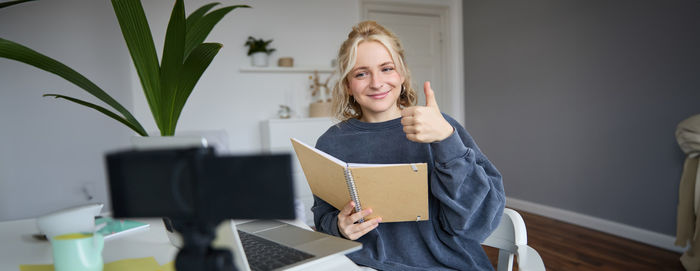 Portrait of young woman using digital tablet while sitting at home