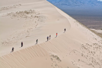 High angle view of people walking on sand dunes at desert