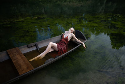 Woman lying in a wooden boat on a river