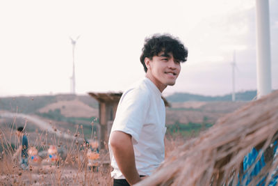 Smiling young man on field against sky