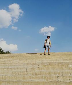 Young man standing on steps against sky