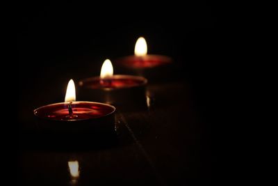 Close-up of illuminated candles in darkroom