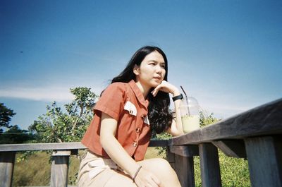 Young woman looking against sky