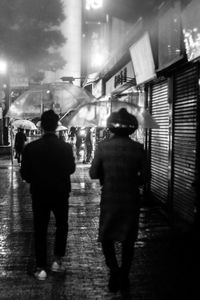 Rear view of people walking in illuminated city