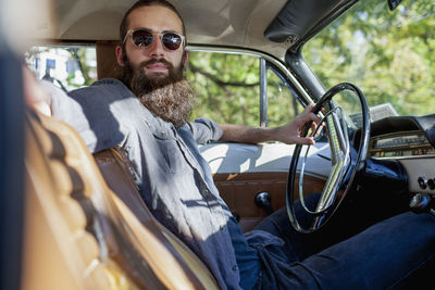 Looking across the front seat of bearded man in a vintage car