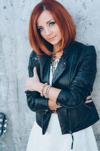 Portrait of woman with arms raised standing against wall