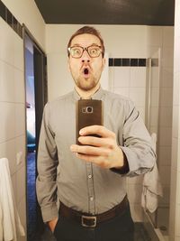 Portrait of man using mobile phone in bathroom