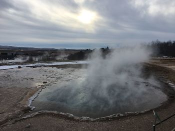 Scenic view of strokkur over landscape against sky