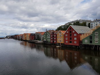 Buildings by river against sky