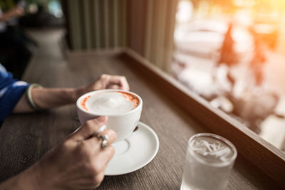 Midsection of woman holding coffee cup on table