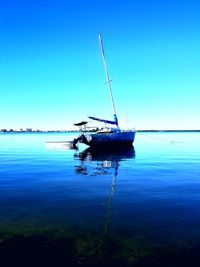 Ship moored on sea against clear blue sky