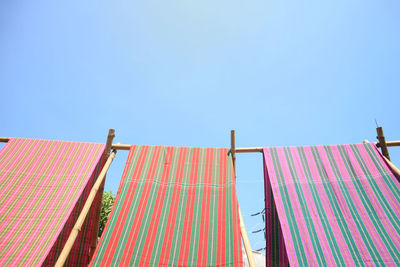 Low angle view of drying against buildings against clear blue sky