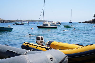 Boats moored at harbor against clear sky