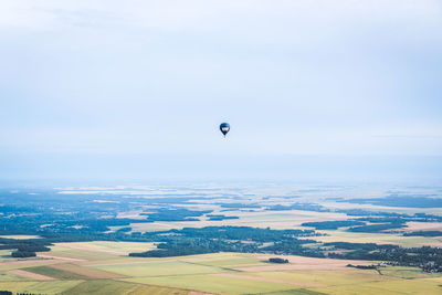 Hot air balloons flying over field against sky