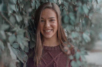 Portrait of smiling young woman standing amidst plants 