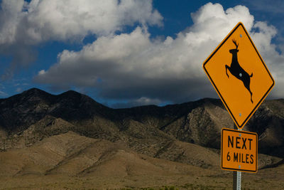 Road sign against mountains and sky