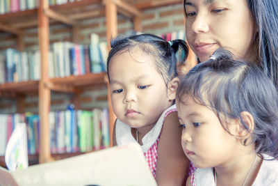 Mother showing book to daughters at home