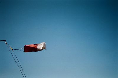 Low angle view of flag against clear blue sky